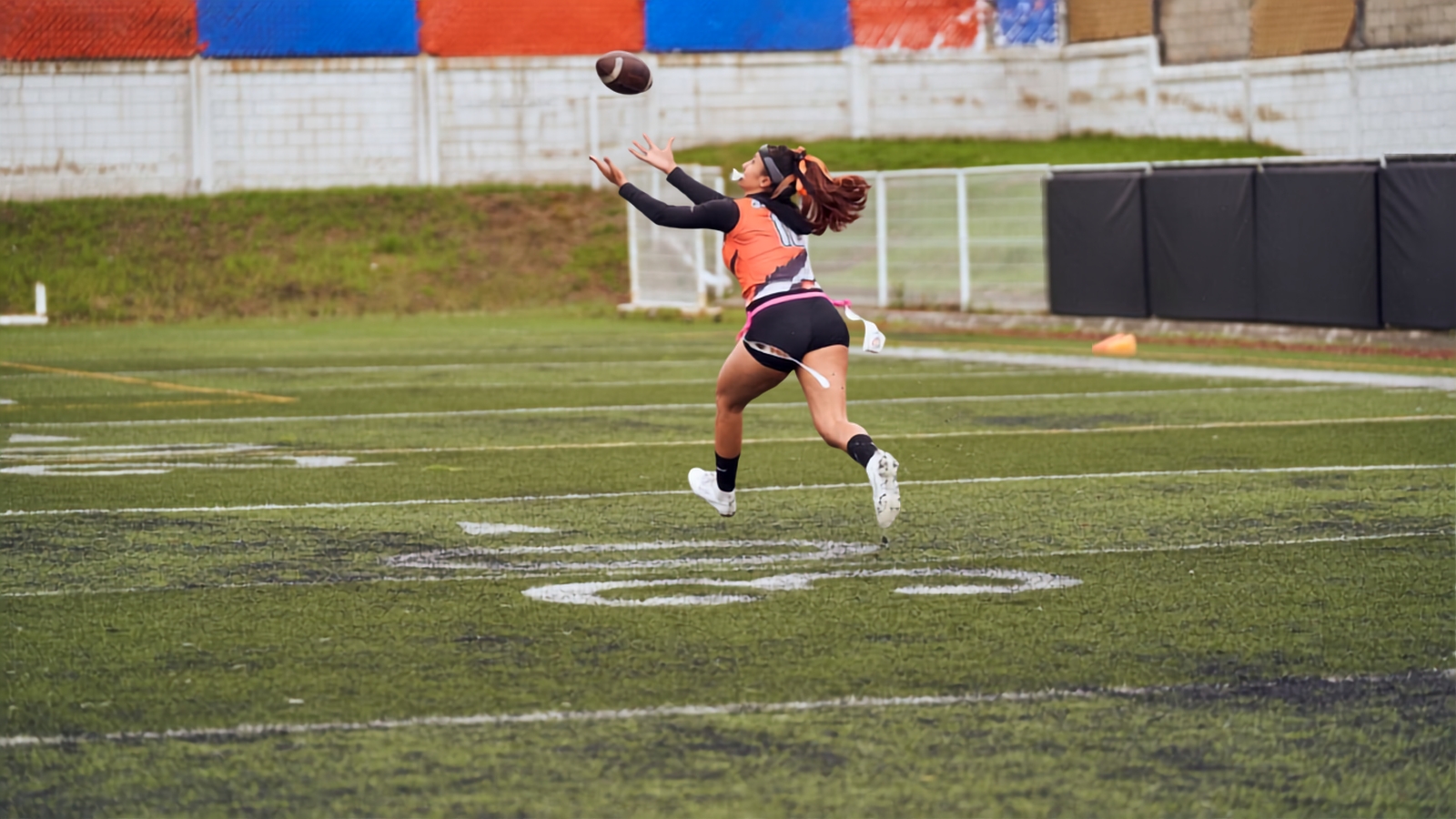 Female athlete catching a football on a flag football field